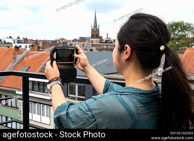 Portrait of a 32 year old Japanese woman, taking a photo with her smartphone, Belgium