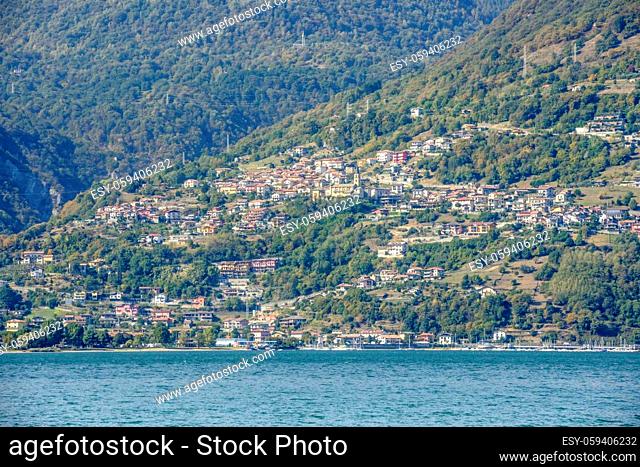 landscape of green lake coast of Como lake with Vercana hill village, shot in bright fall light from Colico, Lecco, Italy