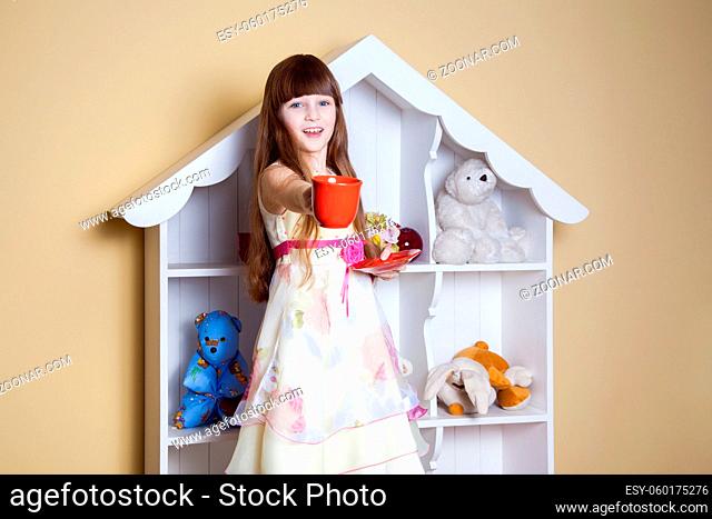 Happy little girl with cup of tea in her room. drinking and happy. studio shot