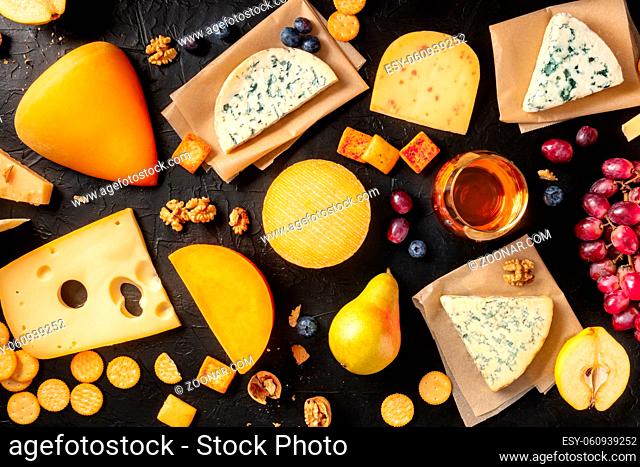 Cheese, wine, and fruit. A variety of cheeses, shot from above on a black background