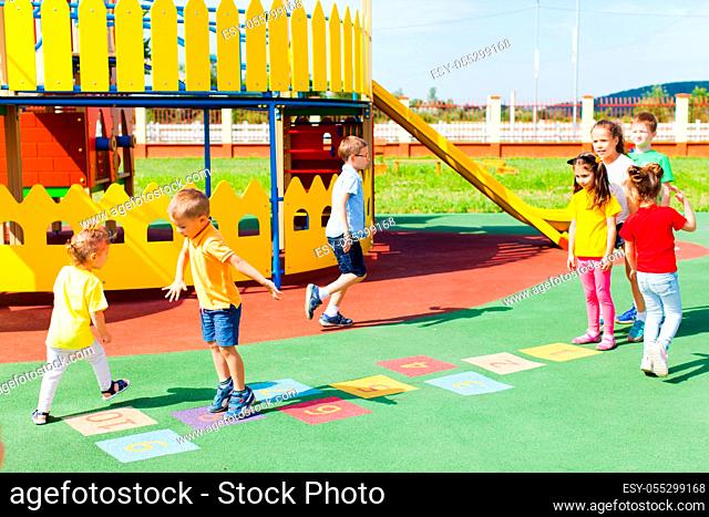 Group of kids play hopscotch on the playground. Children jump and run in turn
