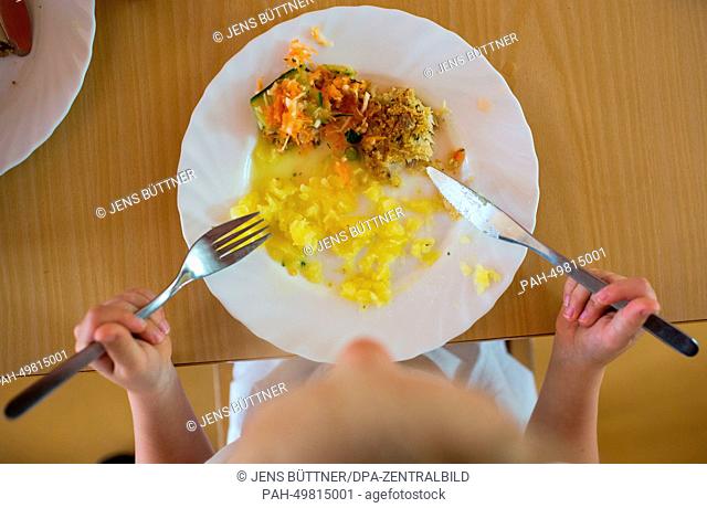 Nursery child Lilly eats her lunch from her plate with a knife and fork at the integrated nursery 'Plappersnut' in Wismar, Germany, 19 June 2014