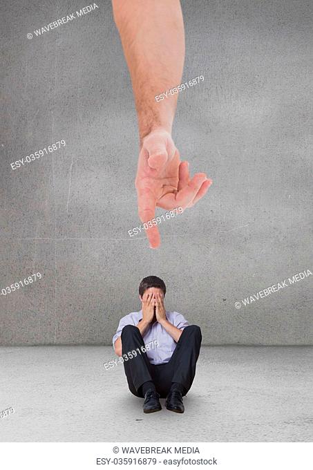 Hand pointing at sad business man against grey background
