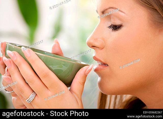 Closeup portrait of beautiful girl drinking tea, side view