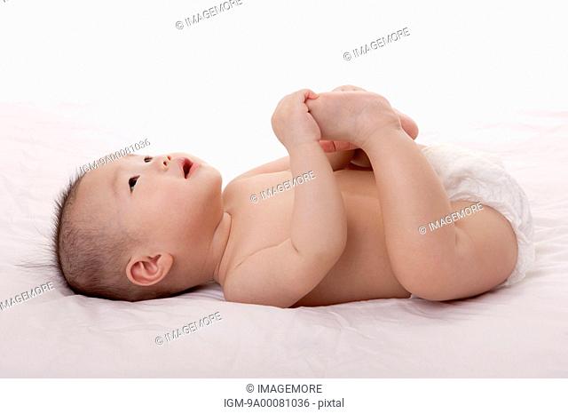 Baby girl lying on back, holding feet