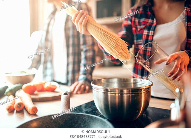 Couple cooking fresh vegetable salad and spaghetti on the kitchen. Diet food preparation. Couple prepares romantic dinner, healthy lifestyle