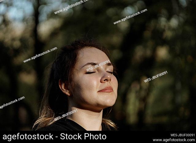 Smiling woman with eyes closed enjoying in nature fresh air in park