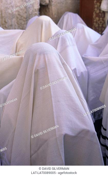 Western, wailing wall. Sukkot festival observance. Figures in white shrouds. Heads covered