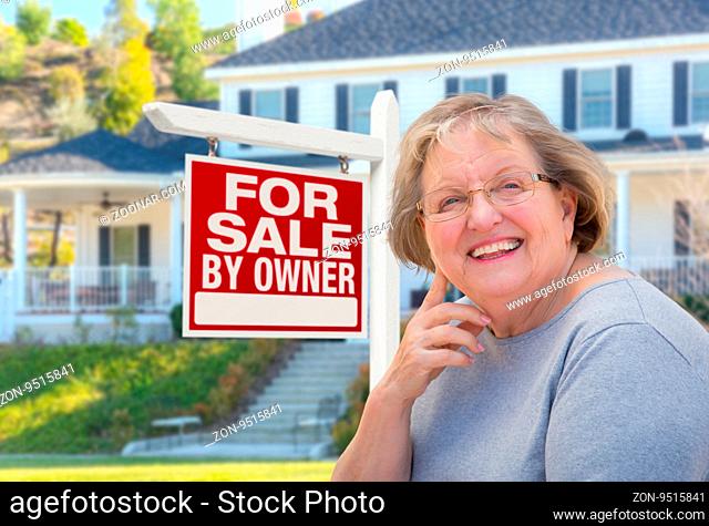 Senior Adult Woman in Front of Home For Sale By Owner Real Estate Sign and Beautiful House