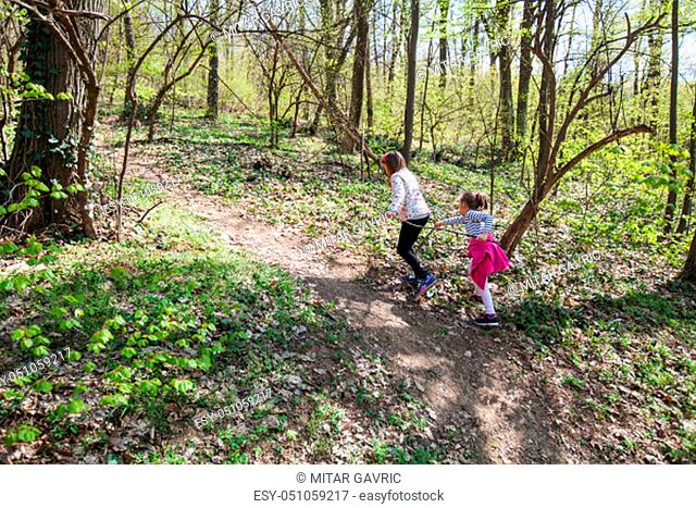 Two little girls hike in forest at spring day