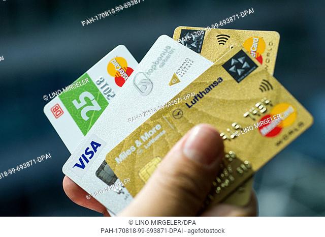 ILLUSTRATION - Credit cards by different private companies being held by a hand in Berlin, Germany, 18 August 2017. From right to left: Lufthansa, Air Berlin