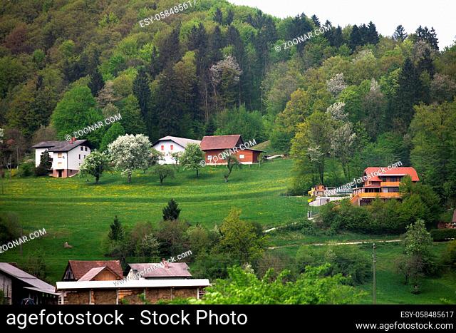 Small holiday village under the mountain. Picturesque view of mountainous area overgrown with green forests with small country houses lost among nature