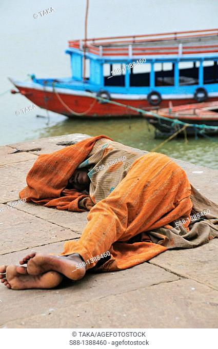 Woman sleeping at the ghat by the Ganges river