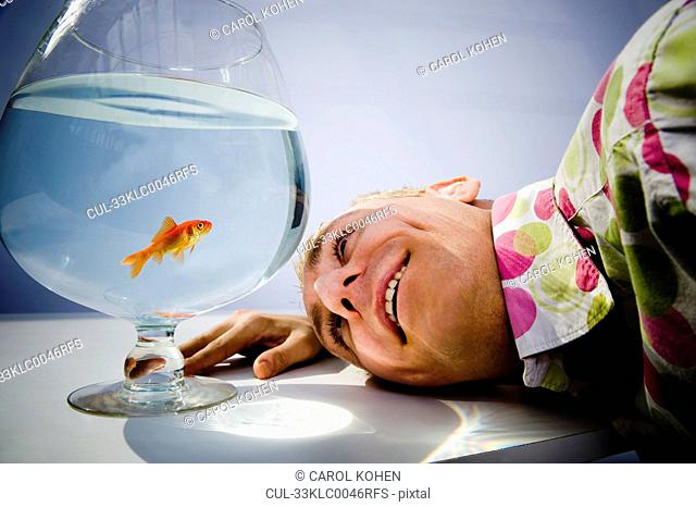 Man admiring goldfish in bowl