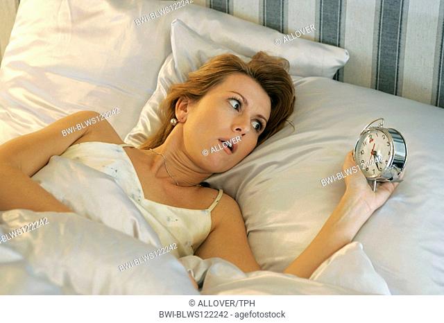 woman awaking by alarm clock in the morning