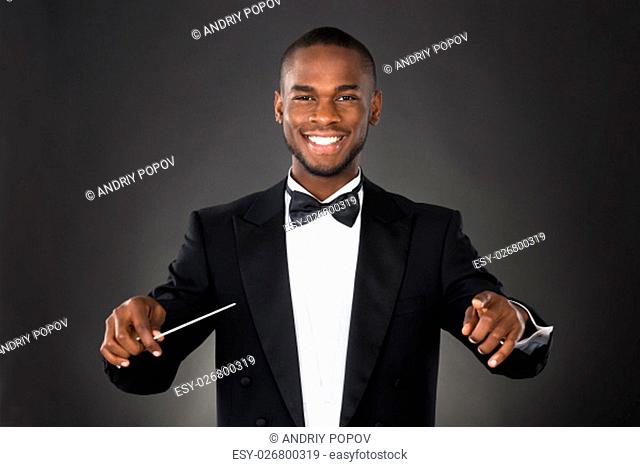 Portrait Of Happy Music Conductor With Baton Against Black Background