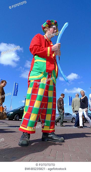 colourful clothed strret clown forming animals with air balloons, Netherlands, Noordwijk