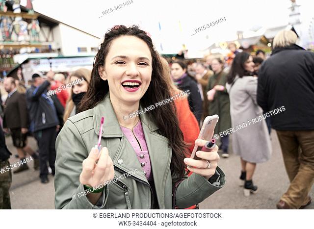 Woman applying lip gloss. Oktoberfest, Bavaria, Germany