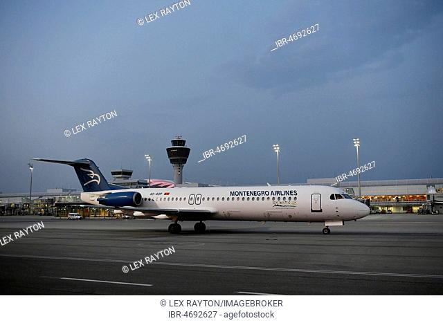 Montenegro Airlines, Fokker, F100, taxiing in front of Terminal 1 with tower, at dusk, Munich Airport, Upper Bavaria, Bavaria, Germany
