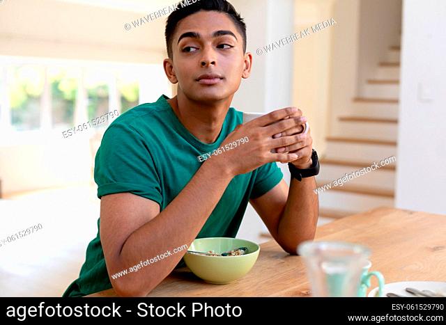 Mixed race man sitting at table and eating breakfast