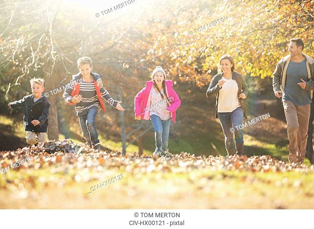 Family running in park with autumn leaves