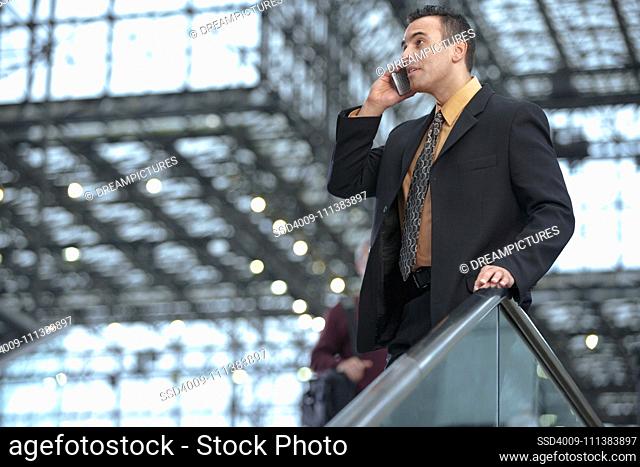 Hispanic businessman talking on cell phone in lobby