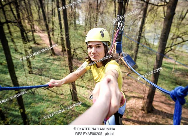 young smiling woman giving her hand in a rope course