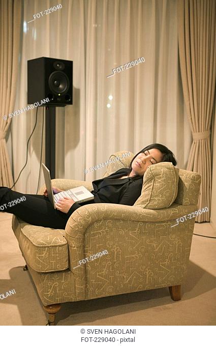 Woman resting in arm chair holding laptop, Tokyo, Japan
