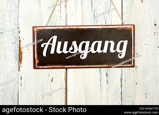 Old metal sign in front of a white wooden wall - Ausgang - German word for Exit