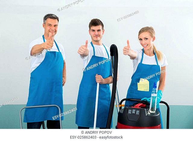 Group Of Happy Janitors With Cleaning Equipments Showing Thumb Up Sign