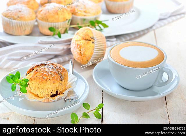Freshly baked chocolate banana muffins with icing sugar served with a cup of cappuccino