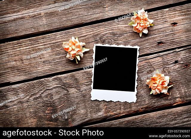 Blank instant photo frame with dried flowers on old wooden background