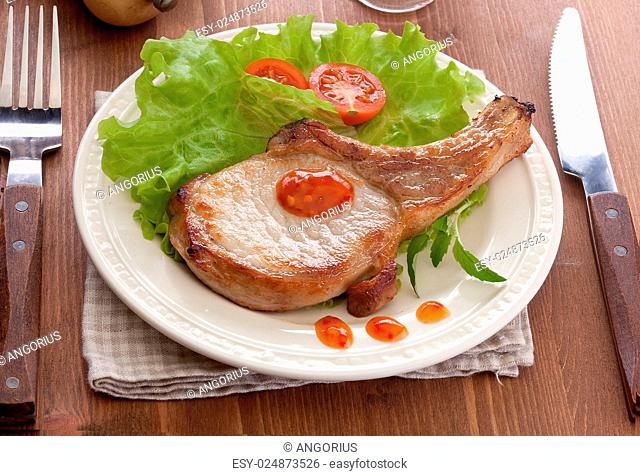 Fried pork cutlet with fresh green lettuce, tomato and sauce on the white plate