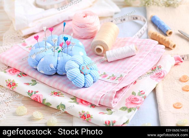 Sewing tools and supplies - handmade pincushion, scissors, bobbins with thread, needles and fabric. Hobby, crafting, creativity, free time at home concept