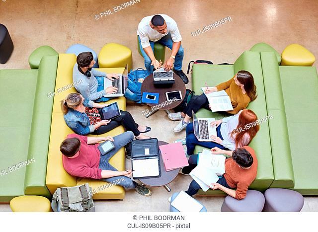 Overhead view of seven male and female students brainstorming in higher education college study space