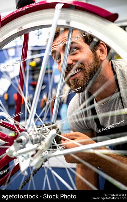 Mechanic repairing bicycle wheel in workshop