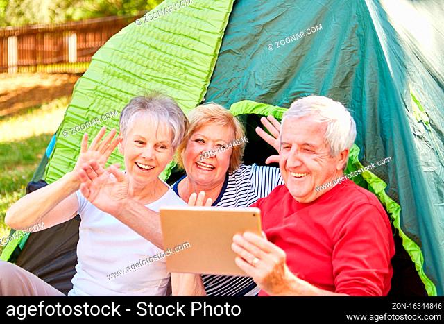 Fröhliche Senioren machen Foto mit dem Tablet PC vor dem Zelt beim Camping