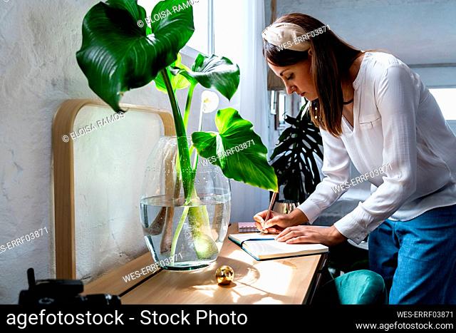 Woman writing in diary at desk