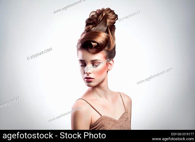 portrait of attractive brunette woman with stylish hairdo and makeup posing with closed eyes on isolated grey background