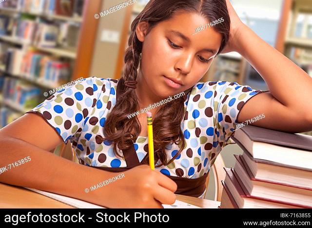 Hispanic girl student with pencil and books studying in library