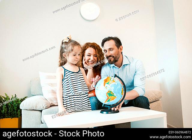 Going on adventure, mom, dad and daughter studying globe. Happy family planning vacation