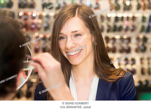 Woman in opticians assisting customer, smiling