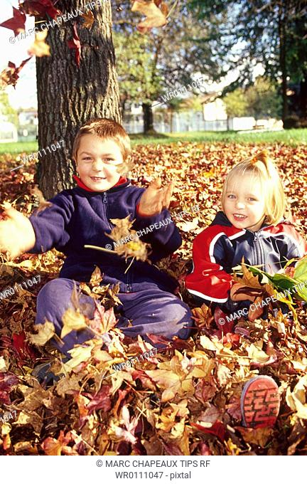 Brother and sister playing with leaves