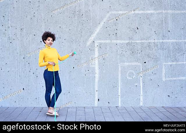 Young woman with green plug standing in front of painted house