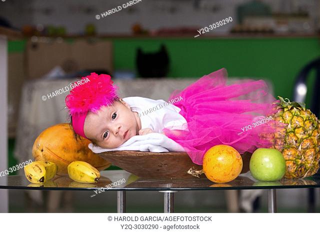 Baby lying in a basket of fruit on the table