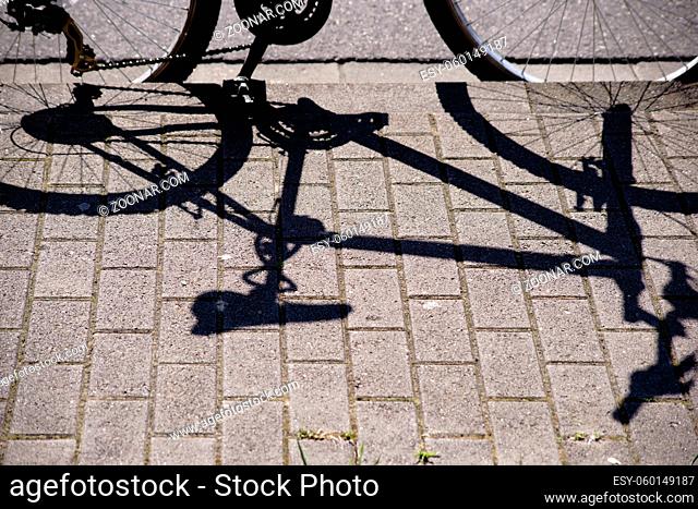 Ein geparktes Fahrrad wirft einen Schatten auf den Gehsteig