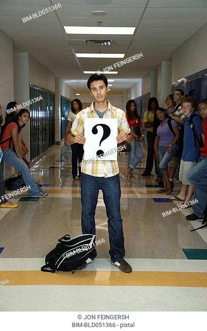 Hispanic teenaged student holding question mark sign