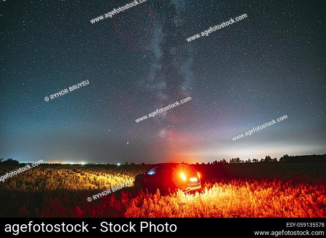 Milky Way Galaxy In Night Starry Sky With Glowing Stars Above Car SUV In Countryside Landscape. Milky Way Galaxy And Rural Field Meadow