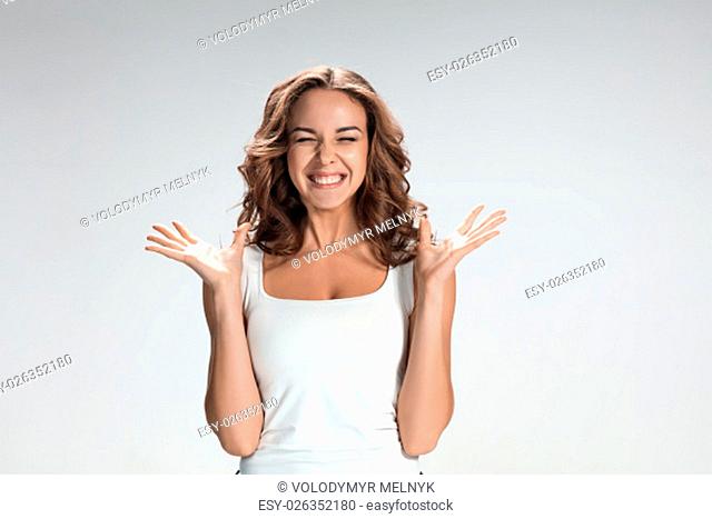 The young woman&#39;s portrait with happy emotions on gray background