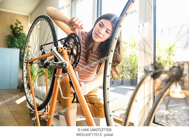 Young woman reparing bicycle at home